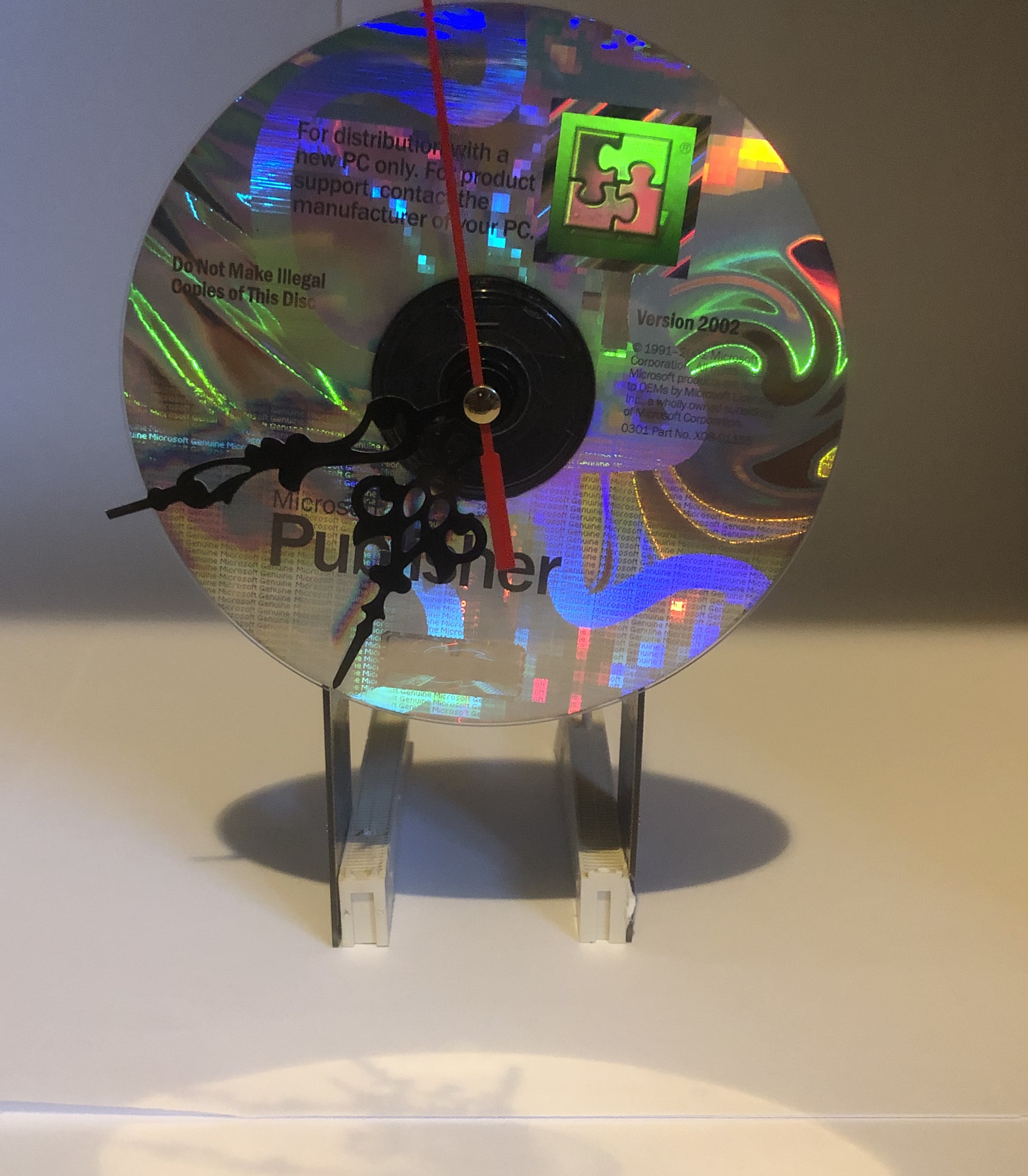 A working wall clock built from an iridescent CD mounted on a stand.