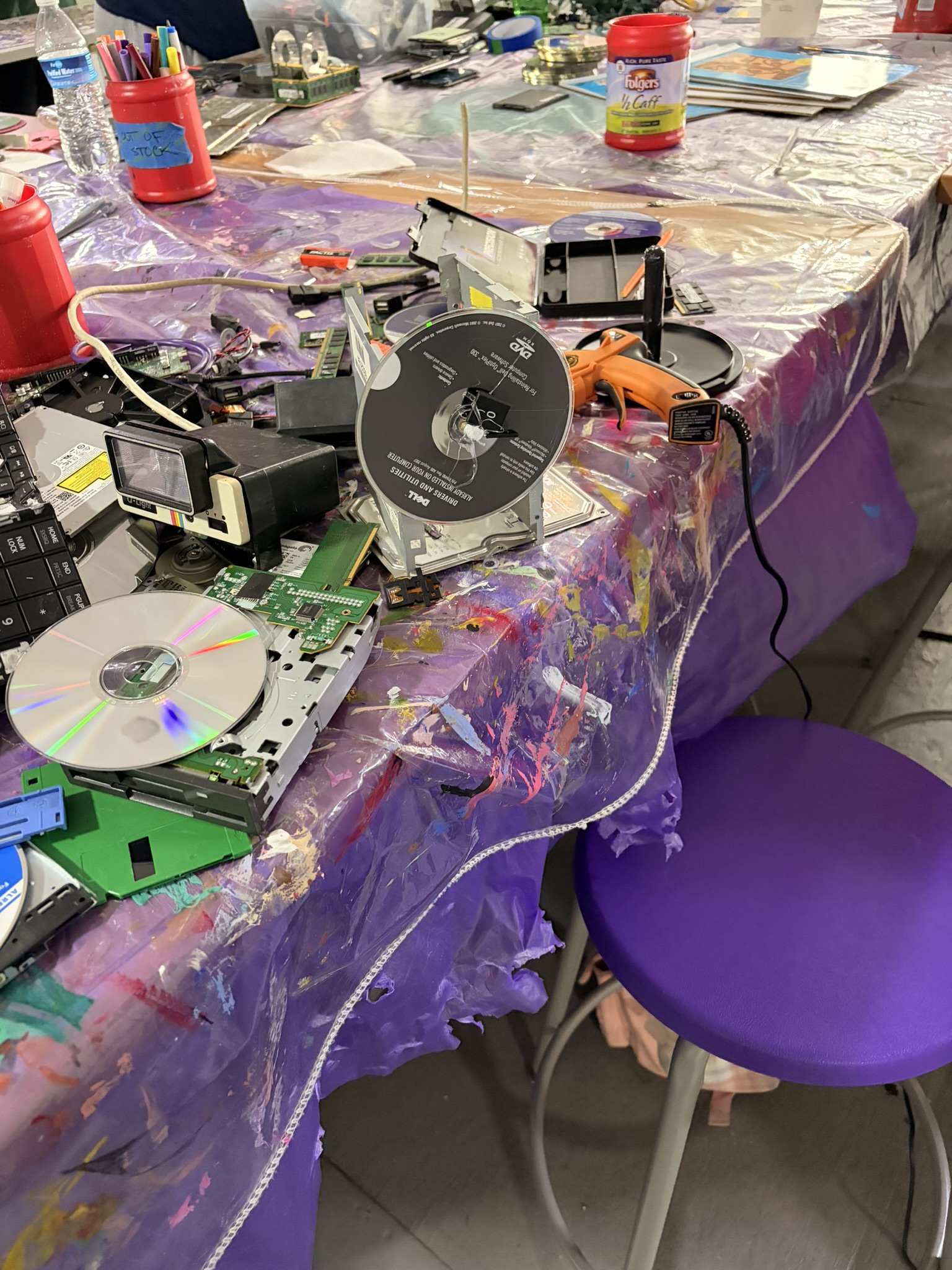 A craft table covered with CDs, circuit boards and tools for an upcycling session.