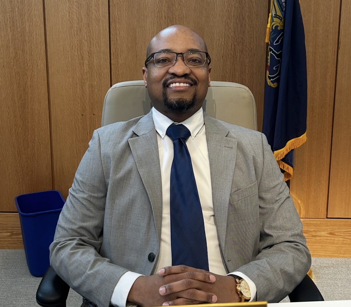 Rashaad sitting down in a chair smiling at the camera.